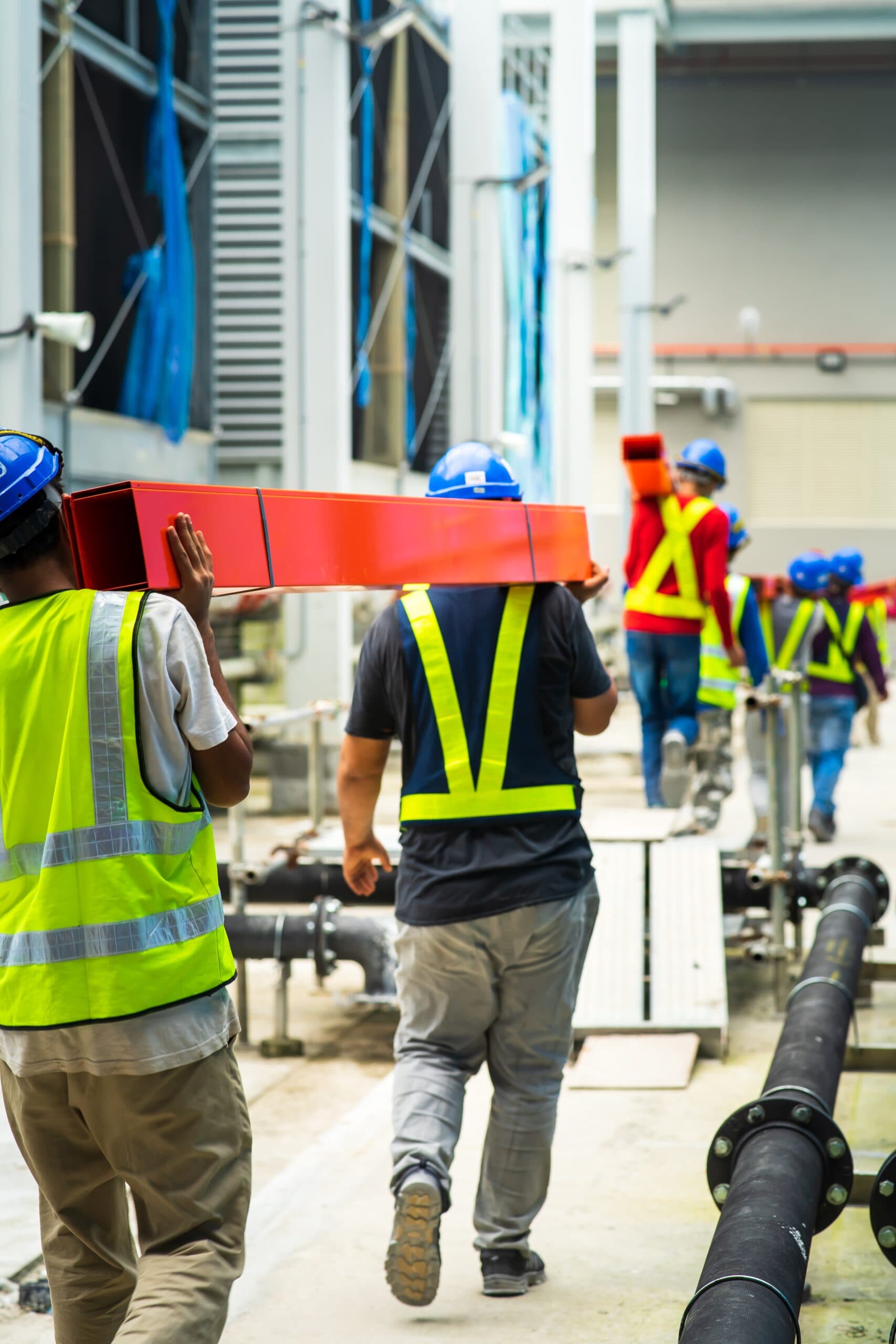Construction crew carrying steel beams on-site: industrial athletes in their work environment